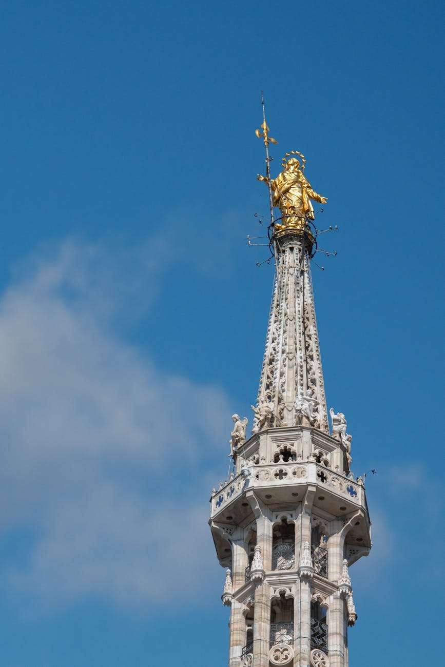 the top of a tall tower with a statue on top